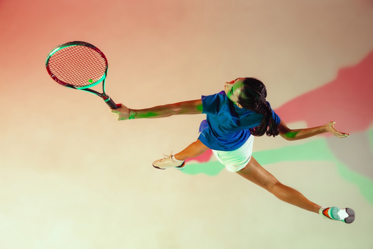 young-woman-blue-shirt-playing-tennis-she-hits-ball-with-racket-indoor-shot-with-mixed-light-youth-flexibility-power-energy-top-view (1)